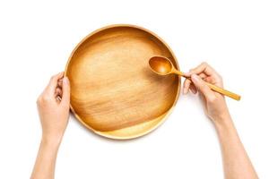 Woman hand hold a circle wooden tray and spoon isolated on white background. photo