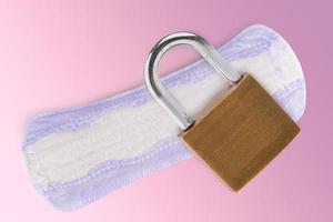 la almohadilla de higiene femenina y la cerradura de metal sobre un fondo rosa foto
