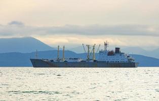 fishing boat in gray morning on Pacific ocean off the coast of the Kamchatka Peninsula photo