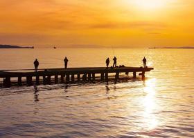 fishermanes silhouette fishing at sunset on the see photo