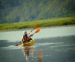 la mujer con un niño en el lago y paseo en kayak foto