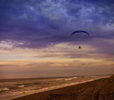 The Silhouette of powered paraglider soaring flight over the sea against sunset sky photo