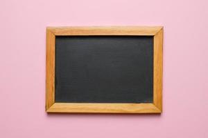 Blank chalkboard with wooden frame isolated on pink background. photo