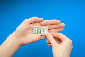 mano de mujer sosteniendo un pequeño billete de 100 dólares estadounidenses foto