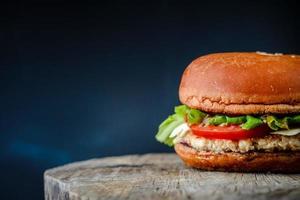 Appetizing homemade burger on a wooden table on dark blue background photo