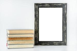 empty black frame and stack of old books on white background photo