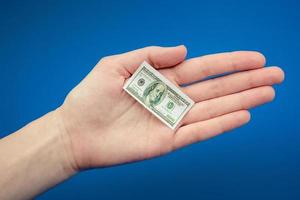 small American dollar bill in hand on a blue background photo