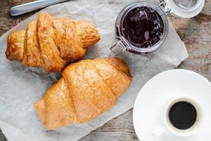 Two croissants and a cup of coffee on a wooden table photo