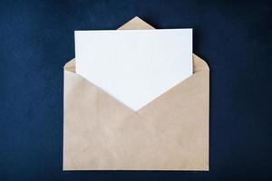 Blank white card in brown enveloop on dark background photo