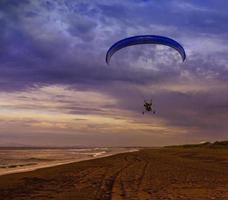 The Silhouette of powered paraglider soaring flight over the sea against sunset sky photo