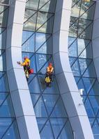 limpiador de ventanas trabajando en un rascacielos moderno con fachada de vidrio foto