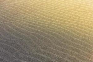 The abstract wave line textures on a Pacific beach illuminated by the Sun and an empty quarter photo