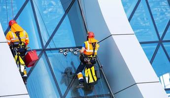 limpiador de ventanas trabajando en un rascacielos moderno con fachada de vidrio foto