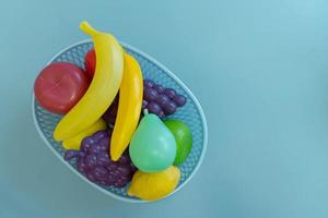 artificial plastic fruit in a basket on a blue background photo