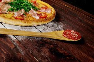 pizza on wood table with ingredients photo