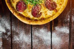 pizza italiana con ternera en una mesa de madera foto