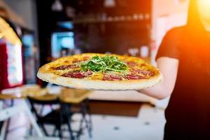 the waiter carries the pizza to the client photo