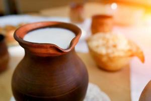 clay jug of milk on the table . Organic food photo