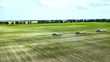 tractors carry bales of straw on the field top view photo