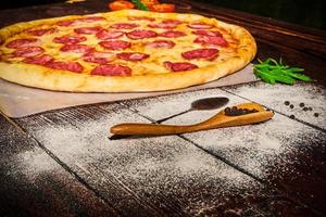 Delicious pizza with vegetables and cheese on a wooden table photo