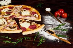Italian fast food. Delicious hot pizza sliced and served on wooden platter with ingredients, close up view. Menu photo. photo