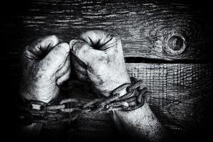 Powerful dirty male hands clenched into fists chained with rusty chain. Black and white photo. photo
