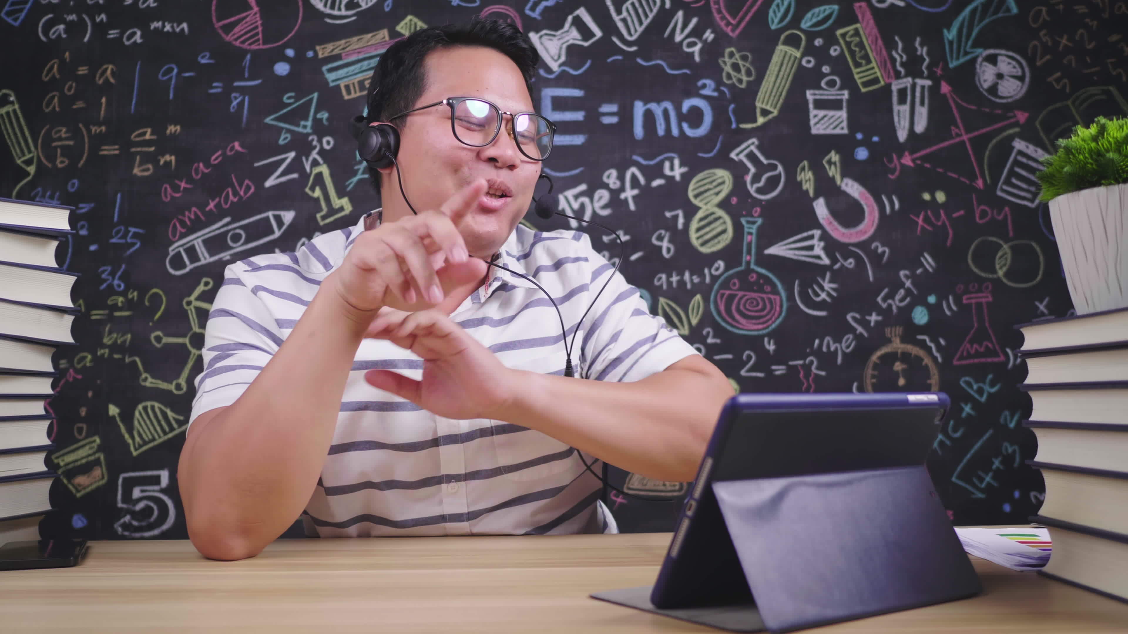 Front View Of Happy Asian Teacher Glasses And Headphone Man Video Call front-view-of-happy-asian-teacher-glasses-and-headphone-man-video-call