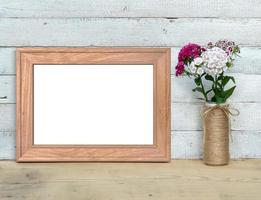 Old Wooden horizontal A4 Frame mockup near a bouquet of sweet-william stands on a wooden table on a painted white wooden background. Rustic style, simple beauty. 3d render. photo