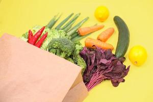 Verduras en bolsa de papel aislado sobre fondo amarillo. foto