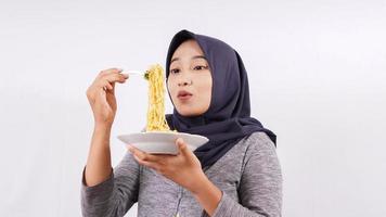 Chica asiática felizmente disfrutando de fideos aislado sobre fondo blanco. foto