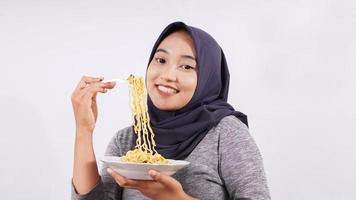 Chica asiática felizmente disfrutando de fideos aislado sobre fondo blanco. foto