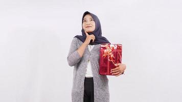 asian girl carrying a gift thinking isolated on white background photo