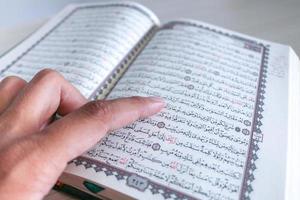 Close up of hand when reading the Holy Quran at the mosque. Selective focus photo