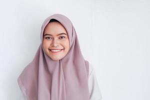 joven islámica asiática con pañuelo en la cabeza con una sonrisa frente a la cámara. mujer indonesia. concepto de belleza aislado sobre fondo gris foto