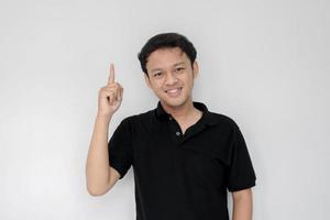 Happy and smile face with smile of young Asian man in black shirt with hand point on above empty space. photo