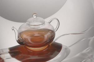 Transparent glass teapot and cup with tea photo