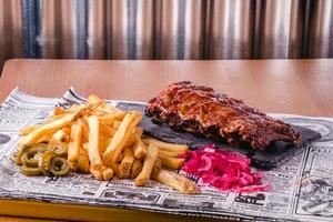 Spicy hot grilled spare ribs from a BBQ served with french fries photo