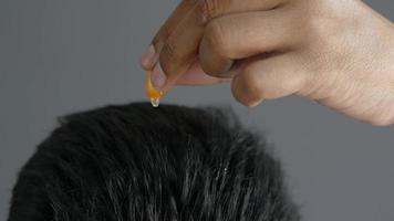 men applying capsule oil on hair video