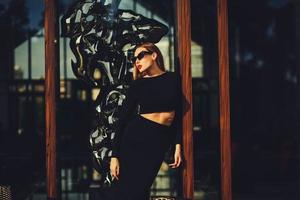 fashion girl posing in sunglasses near the glass windows photo