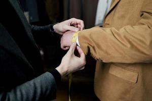 tailor taking wrist measurements from client photo