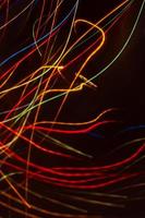 Drawing with light. Abstract multicolored rays on a black background. Curved wave lines. photo