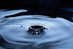 Crown from a splash of water on a dark background. Liquid background with glitter. Small waves. photo