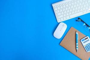 Blank notebook with pen is placed on an office desk table with computer tools and a range of materials. finance and banking background, flat lay, top view photo