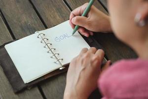 woman writing goal on notebook  at coffee shop outdoor space photo