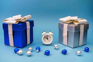 boxes with gifts and christmas tree blue toys with clock on blue background, photo