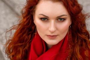 Female portrait with red hair and bright makeup. Red scarf around the neck photo