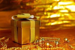 caja de regalo dorada sobre fondo brillante foto
