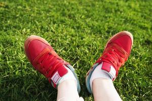 female legs in sneakers on a background of green grass photo