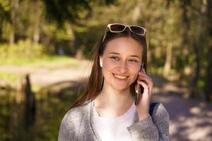 una niña camina y habla por teléfono en un soleado día de primavera foto