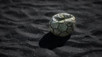 old football ball on the black sand photo